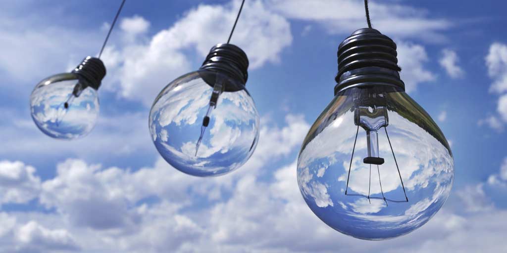 Unlit bulbs hanging downwards, with a bright cloudy sky in the background