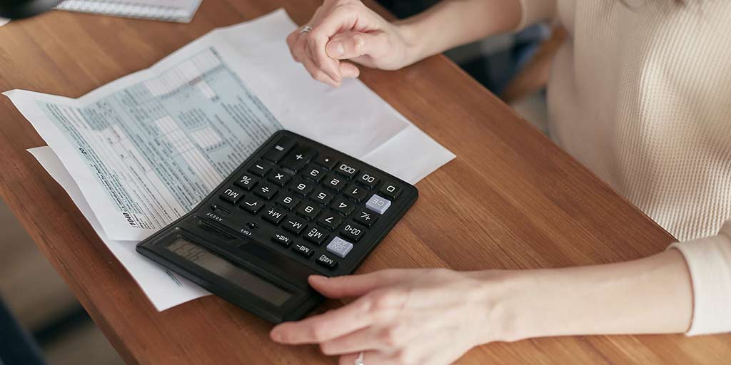 Person sat at desk looking at a form and with a calculator in front of them