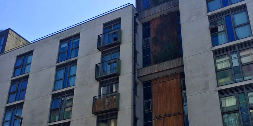 Block of flats with balconies and some cladding on the walls against bright blue sky